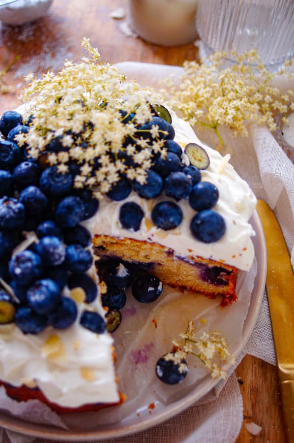 Deze blauwe bessen cake met vlierbloesem is ideaal voor bij de koffie. Een gemakkelijke cake met als geheim ingrediënt zure room en een subtiel vleugje vlierbloesem. Deze blauwe bessen cake wordt afgewerkt met een creme van mascarpone