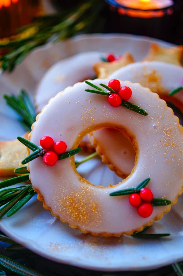 Zijn ze niet schattig deze makkelijke Kerstkransjes koekjes? Je zou ze in je kerstboom kunnen hangen maar daar zijn ze veel te lekker voor. Deze koekjes zijn heerlijk van smaak door de vanille, kaneel, gember en zeste van citroen. Perfect voor bij de koffie en leuk om samen met de kinderen te bakken