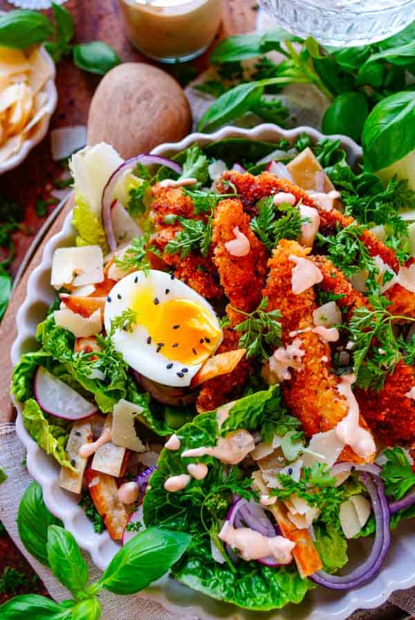 Deze makkelijke Salade met chicken fingers heeft veel weg van een klassieke caesar salade. Een receptje met de lekkerste krokante kip, een eitje, groentjes, wat Parmezaanse kaas en een lekker sausje. Super simpel, snel klaar, gezond en heerlijk van smaak!