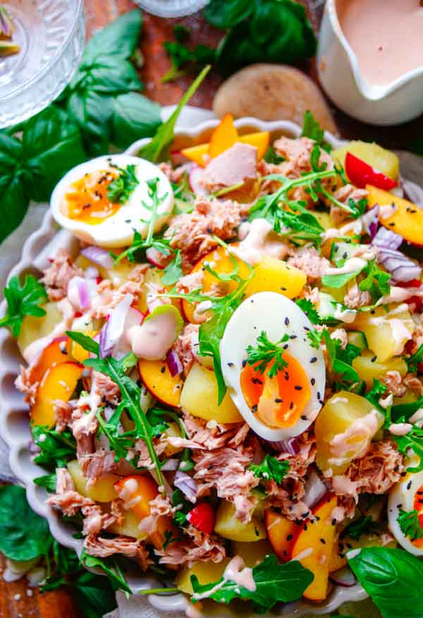 Lekker makkelijk recept voor Aardappelsalade met tonijn, een lichte zomerse avondmaaltijd voor op je weekmenu. Een gezonde salade met aardappeltjes, tonijn, groentjes, gekookt eitje, stukjes perzik en licht cocktailsausje. Snel klaar, makkelijk op voorhand te maken en ideaal om de volgende dag als lunch mee te nemen.