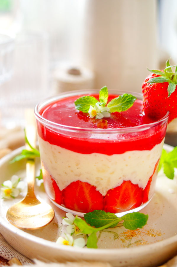 Lekker makkelijk recept voor Rijstpap met aardbeien, een heerlijk simpel zomers dessert dat je makkelijk op voorhand kan maken. Een romige rijst pudding met als geheim ingrediënt witte chocolade. Onderaan in het dessert glaasje vind je verse zomerse aardbeien, daarop de rijstpap afgewerkt met een coulis van aardbeien.